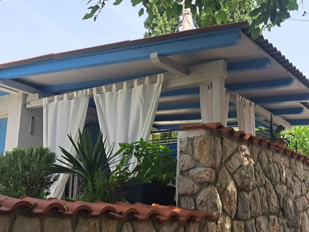 eine große umzäunte Terrasse mit Esstisch und Vorhängen zum Schutz vor Sonne und Aussicht