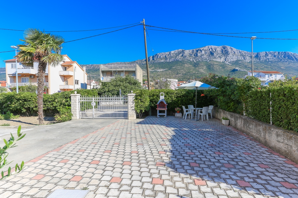 Der Eingang zum Grundstück mit Parkplatz und Grill mit Gartenmöbeln