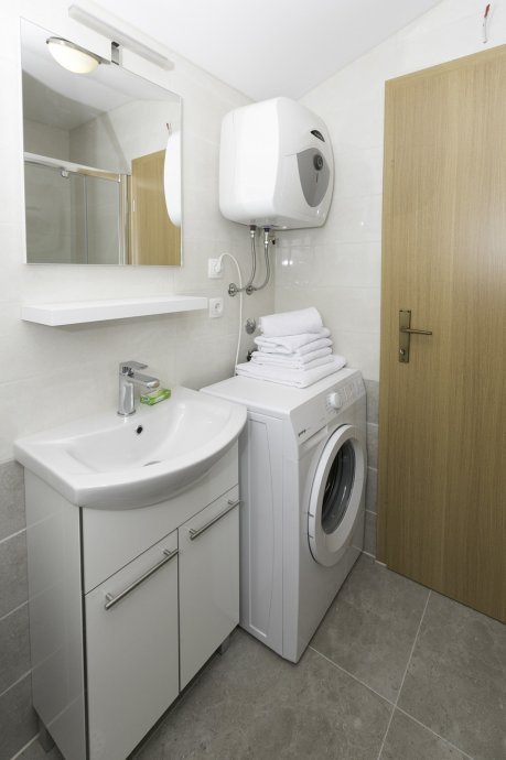 Badezimmerausstattung: Handtücher (groß und klein), Matten, Fön, Handseife, Toilettenpapier und Waschmaschine.