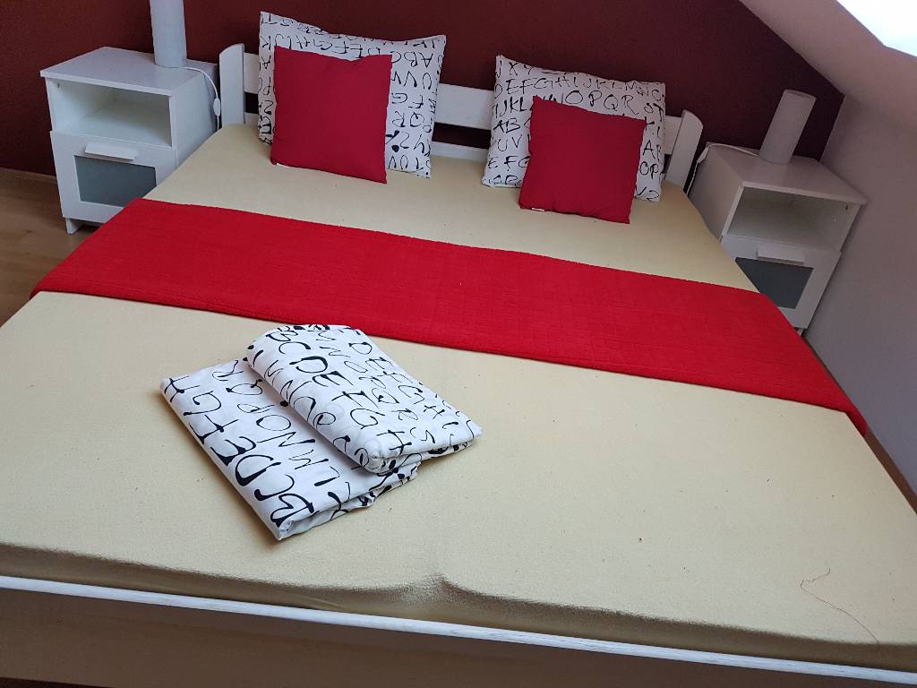 Einfach und gemütlich, das rote Schlafzimmer befindet sich ein Doppelbett mit einer Nachttischlampe, Tisch und viel Stauraum, in der roten Farbe
