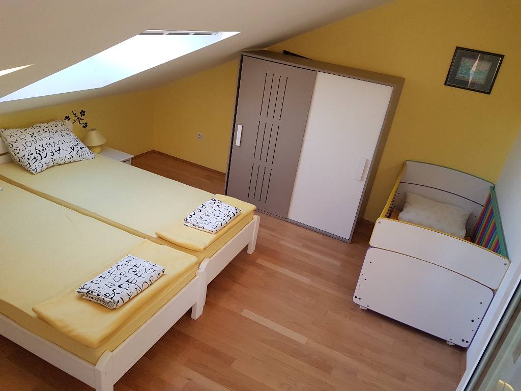 Im Schlafzimmer gibt es ein Kinderbett und ein Doppelbett . Beide Zimmer sind mit frischen Handtüchern